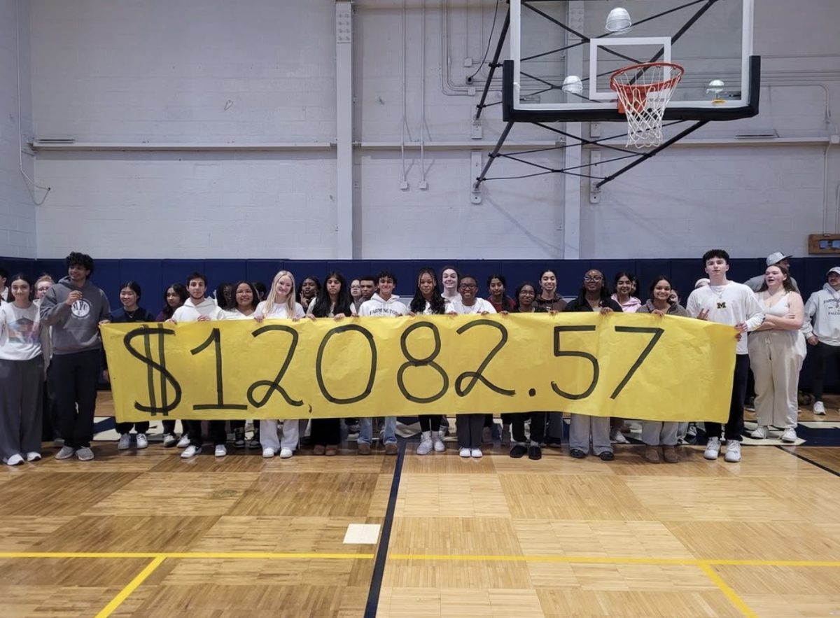 Student council holds a sign that says how much money they are during charity week