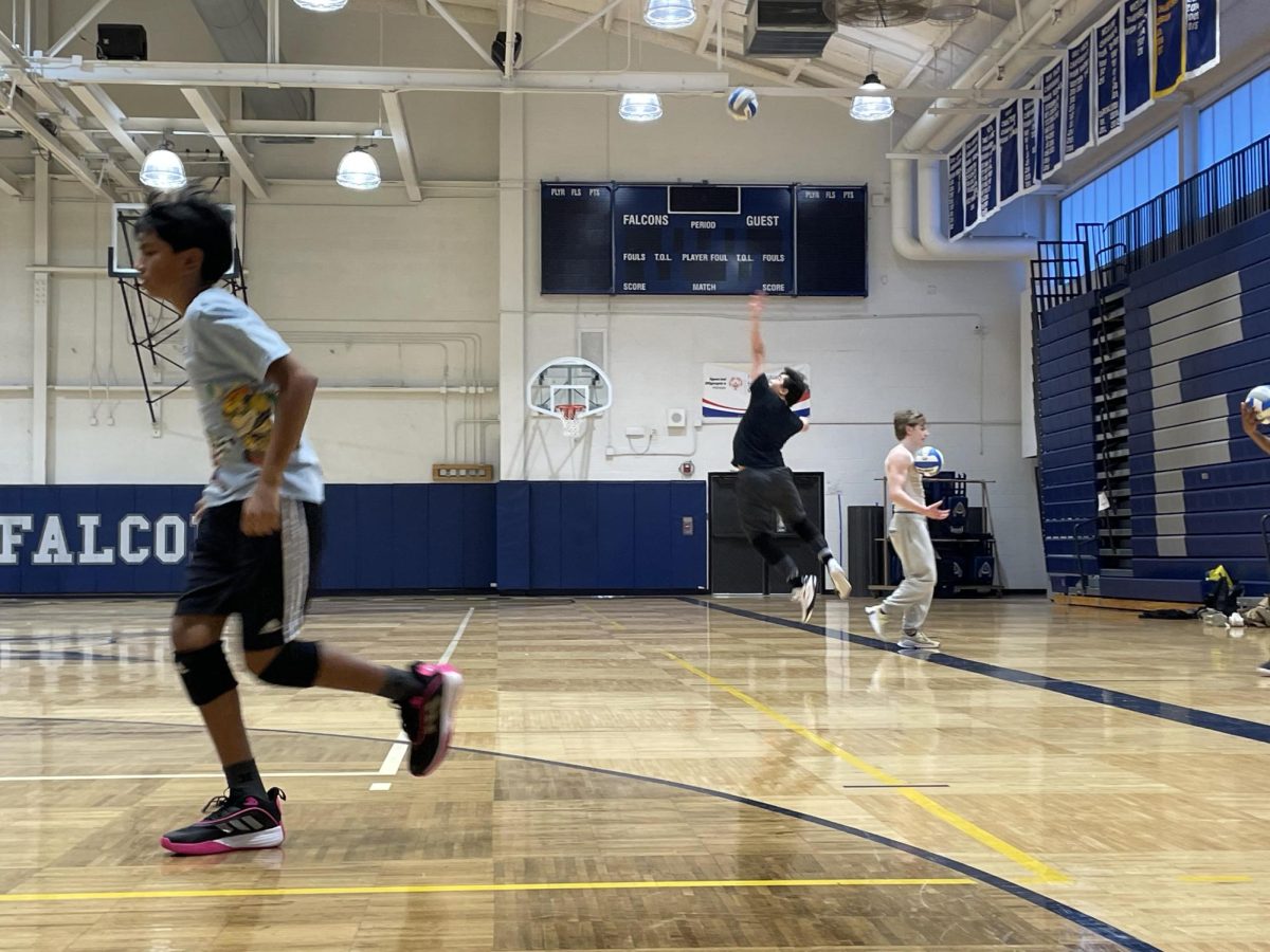 Assistant Teddy Cu makes a jump serve at the baseline.
